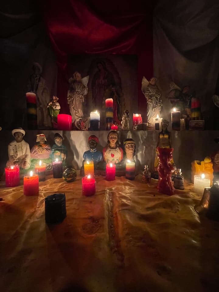 Mi altar con la Virgen de Guadalupe, ángeles y bustos de santos con veladoras.