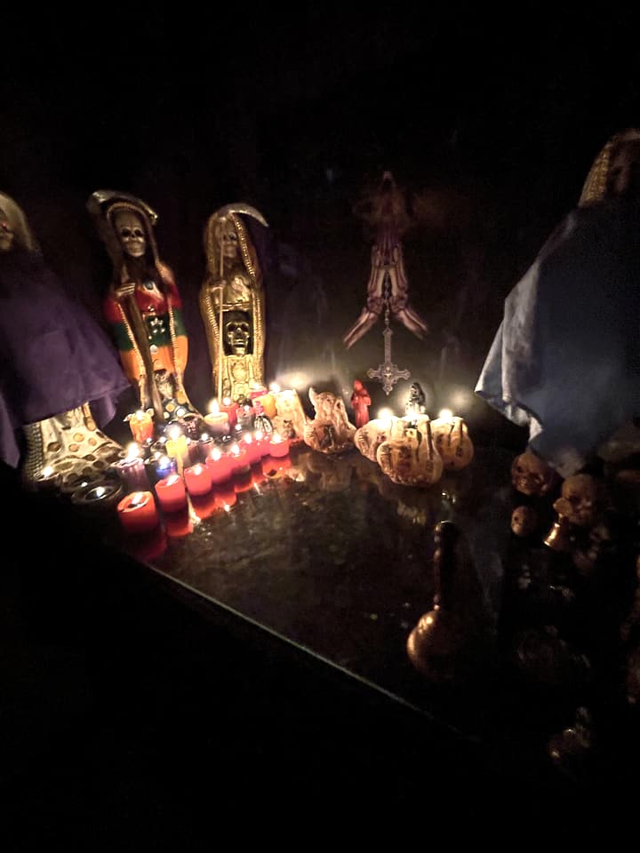 Varias figuras de la Santa Muerte con veladoras rojas encendidas, de noche.